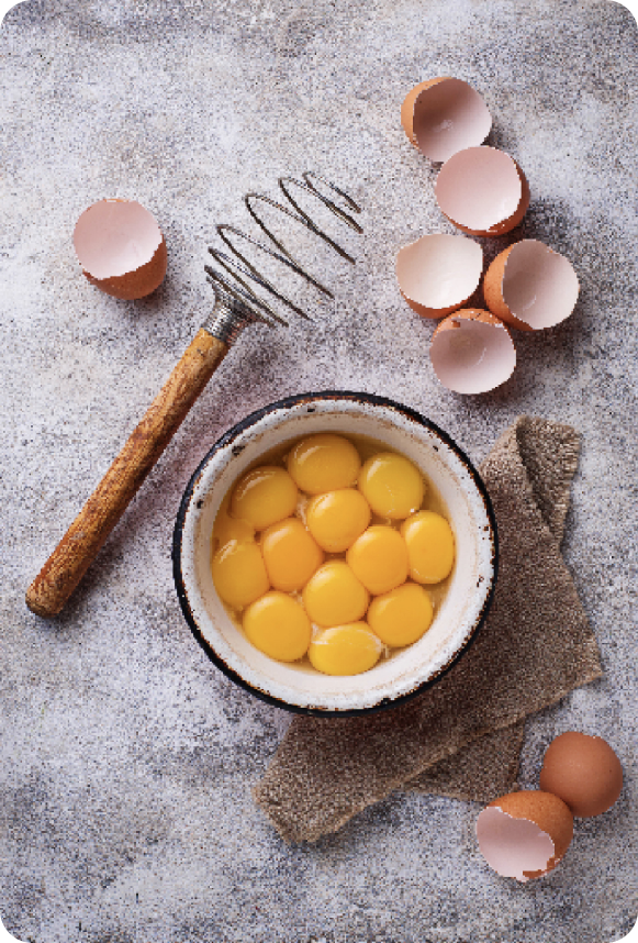 Cracked eggs in a bowl on a counter with a stirring tool